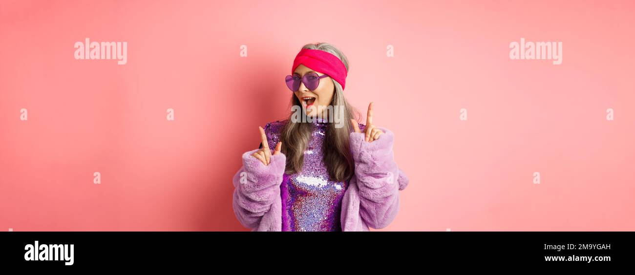 Hipster granny in sunglasses and glittering dress posing for photo with