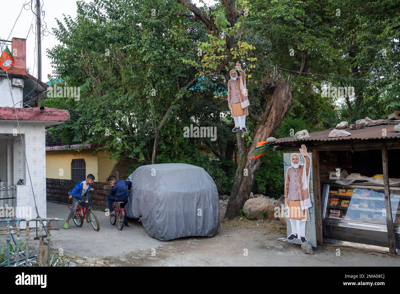 Children ride bicycles next to cut out portraits of Indian Prime ...