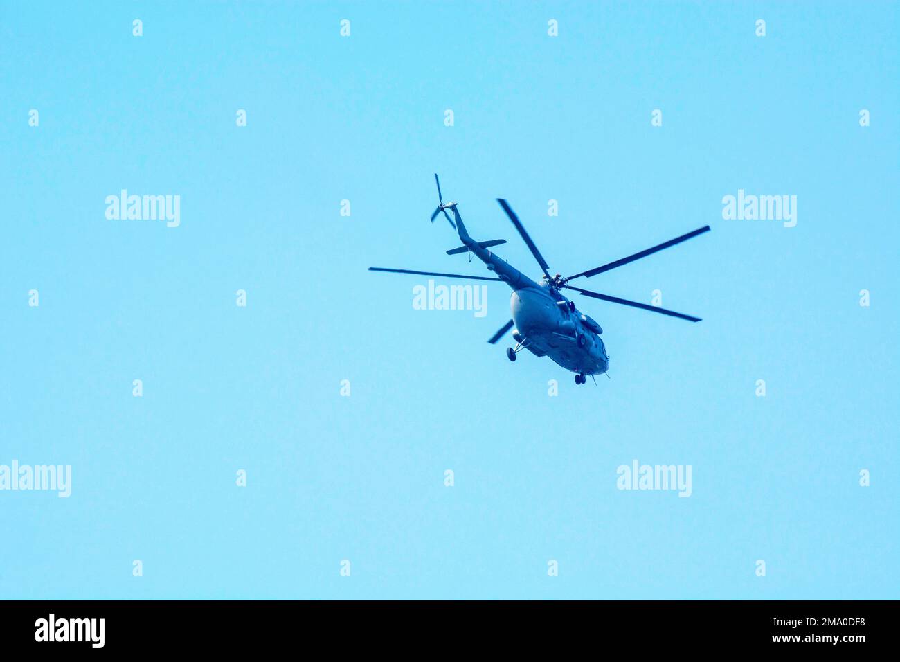 Combat helicopter is flying against isolated blue sky. Combat helicopter attack enemy. Stock Photo