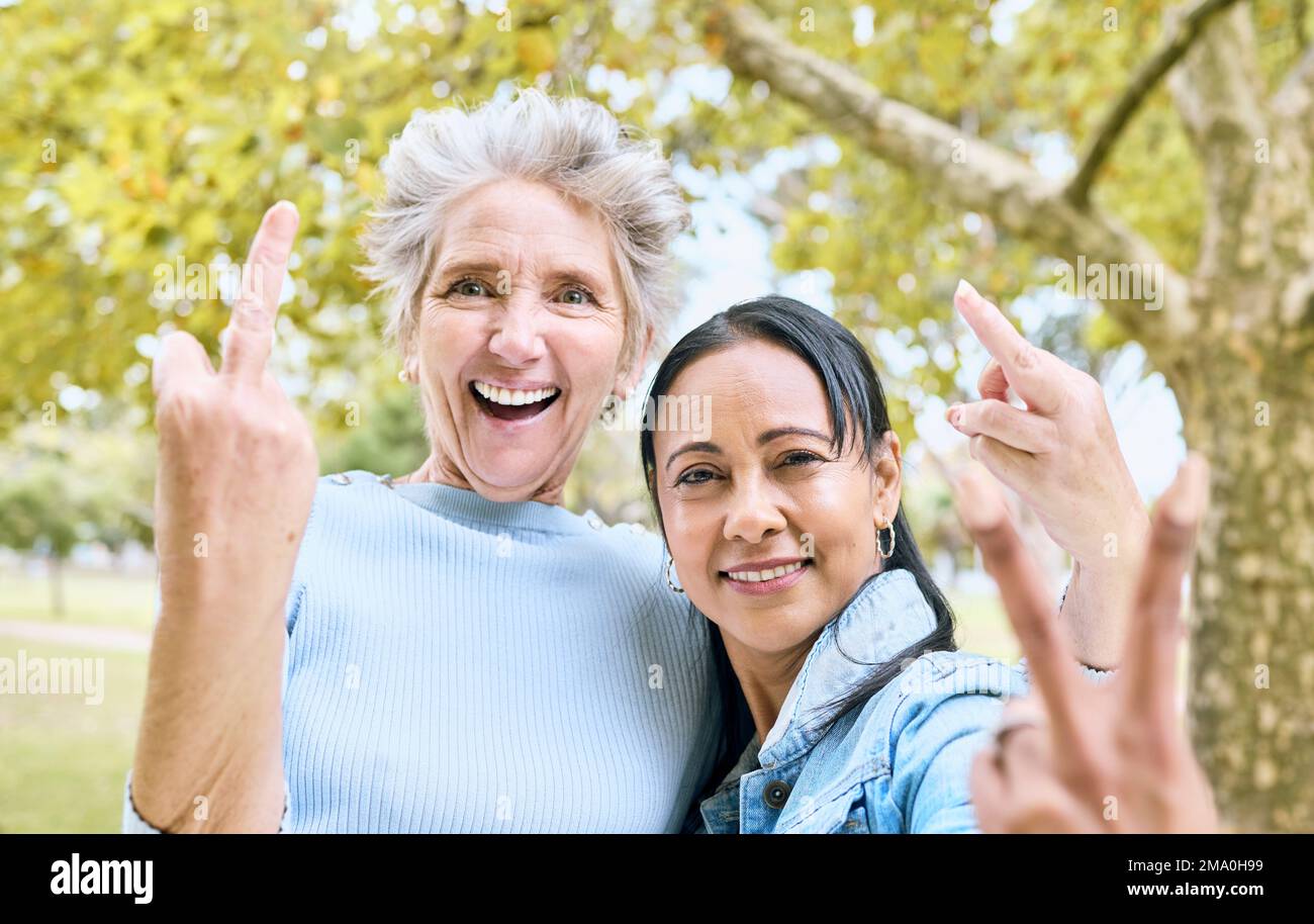 Senior women, park portrait and hand sign for comic, funny and happy time together in nature. Old woman, friends and hands with peace, middle finger Stock Photo