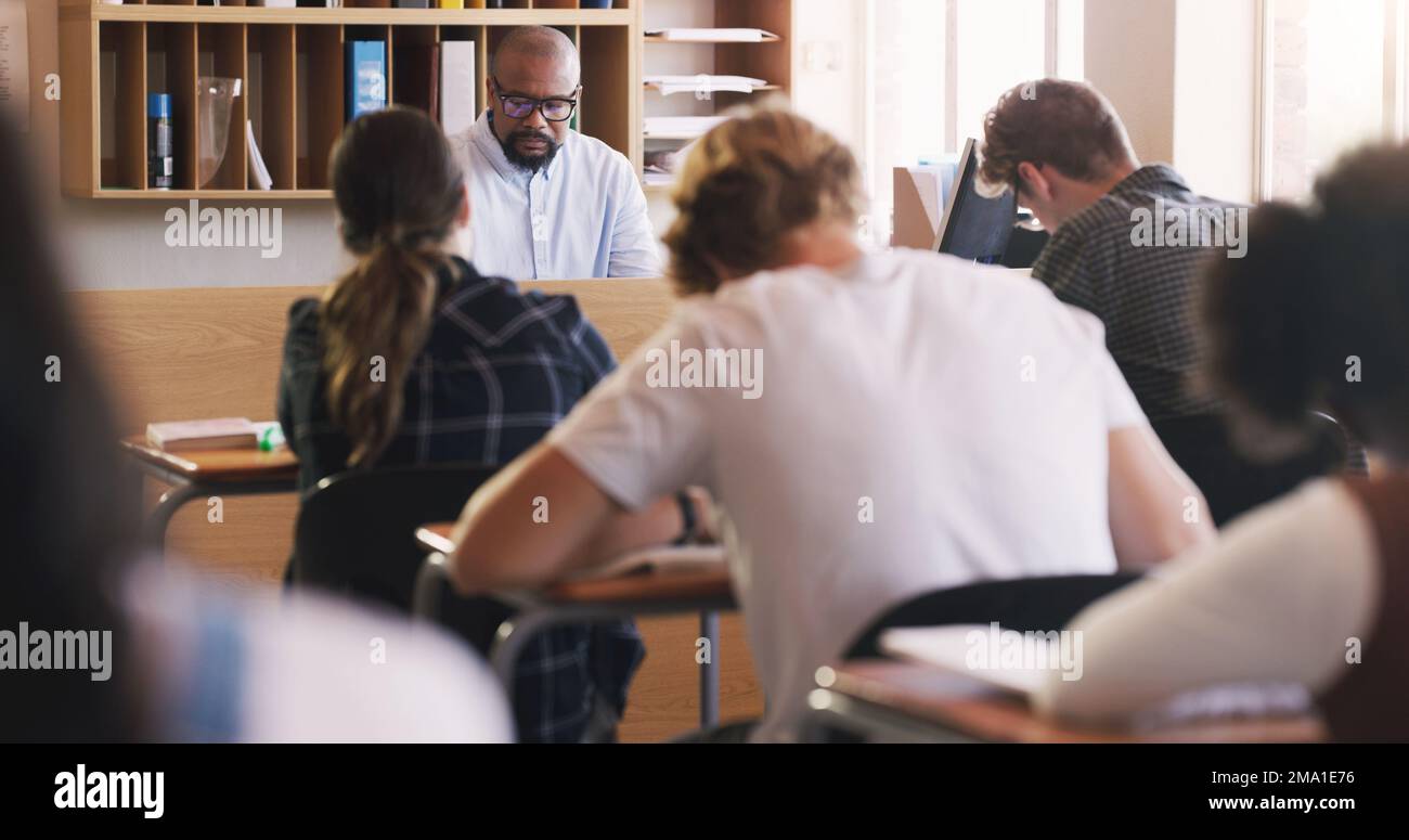 Time spent learning is time well invested. teenagers writing an exam in a classroom. Stock Photo