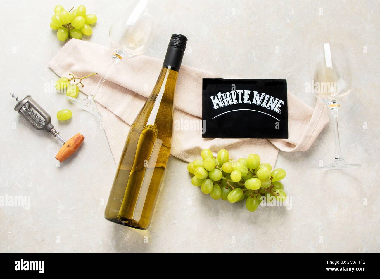 Flat-lay of white wine in glasses and corkscrews on a white background, top view, wide composition. Wine bar, winery, wine degustation concept. Stock Photo