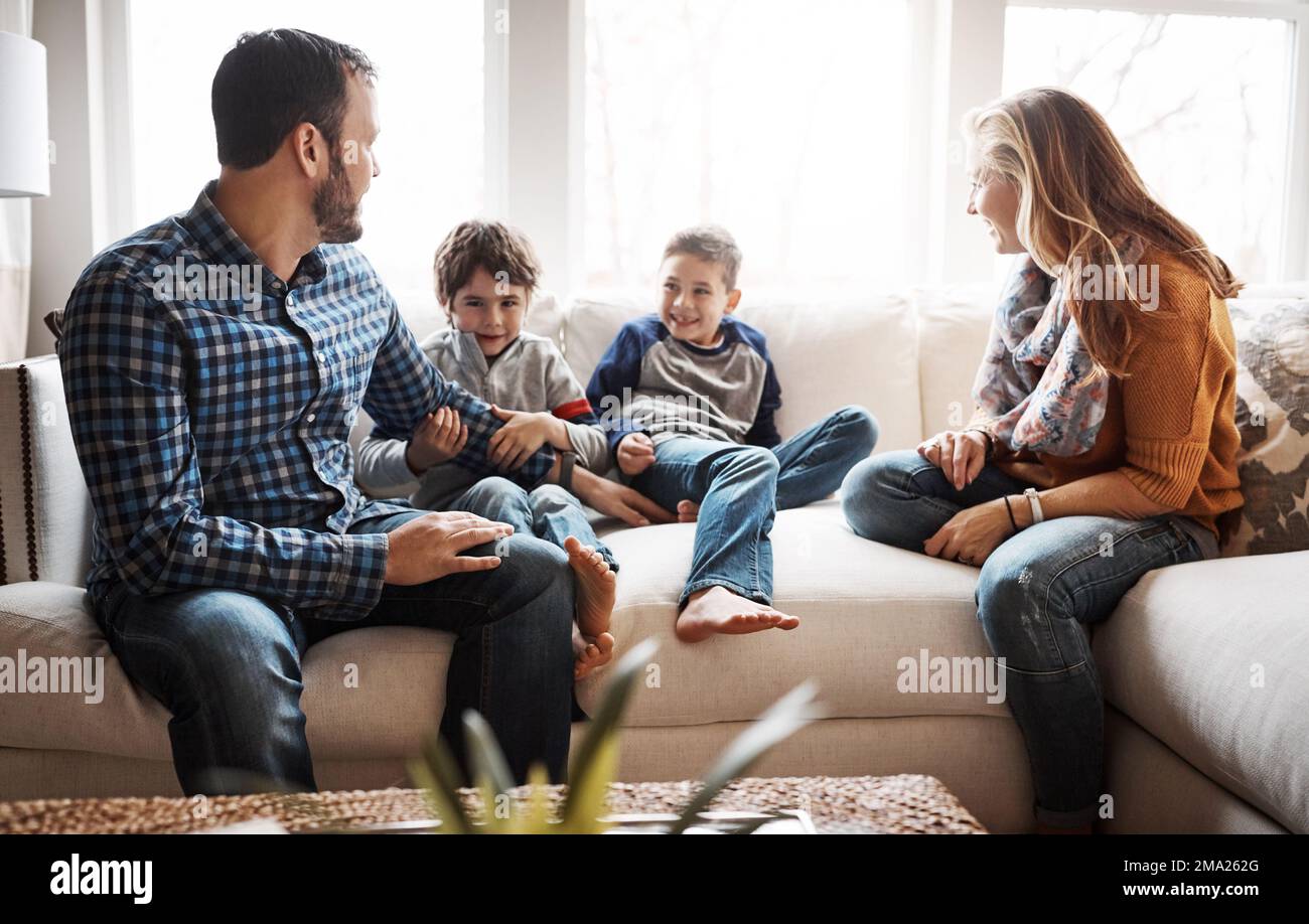 Family home, boy kids and parents on sofa with conversation, love or bonding for childhood development. Happy family, relax and sitting together in Stock Photo