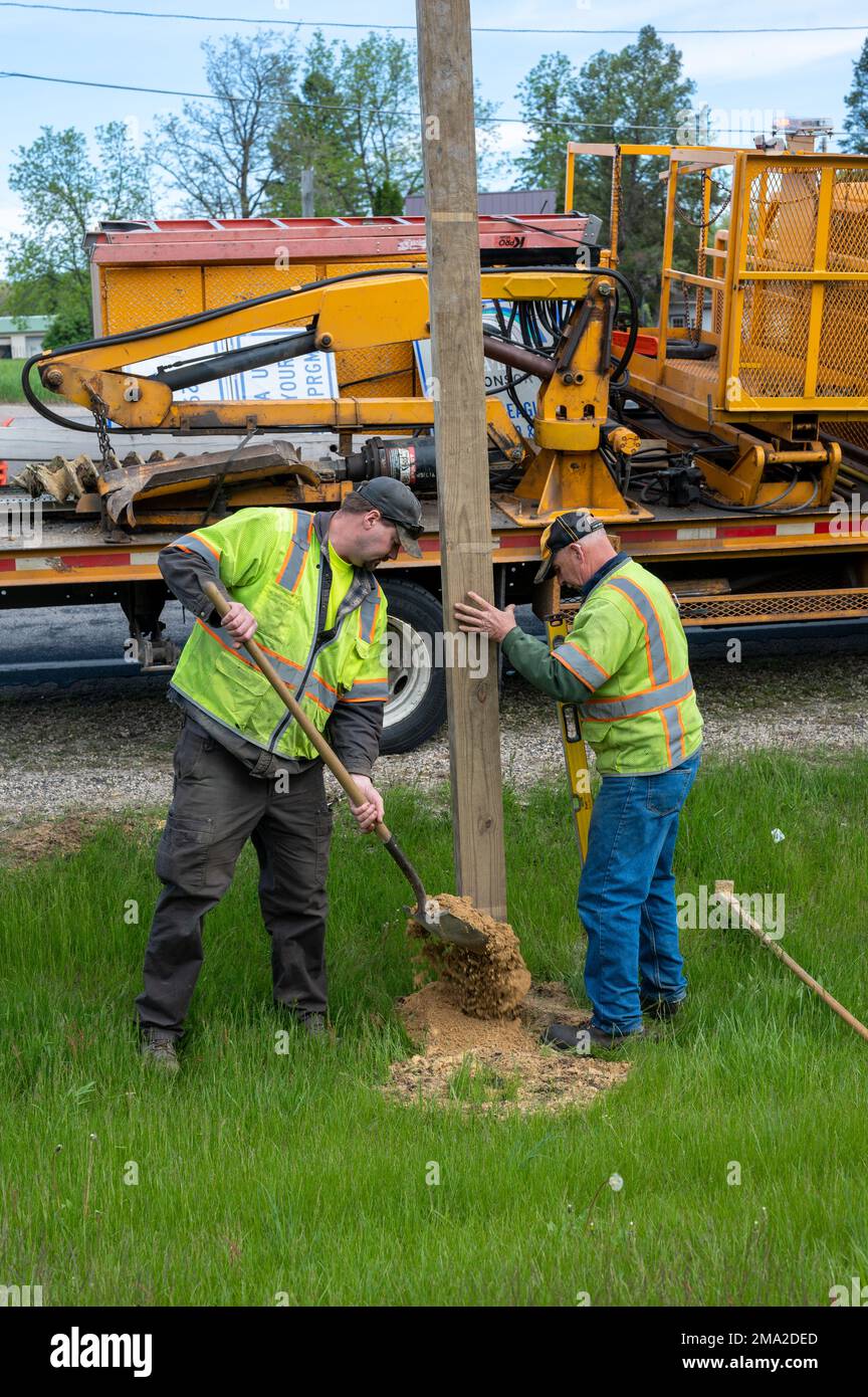 Shaun Oliver, an operations specialist for the Monroe County sign department, left, and Scott Jerome, a section leader for the Monroe County Highway department, right, stabilize a signage pole with cement May 23, 2022, in Sparta, Wis. Soldiers of 1st Brigade Support Battalion, 291st Infantry Regiment, 181st Multifunctional Training Brigade, adopted approximately 2.3 miles of Highway 21 in Sparta. Stock Photo