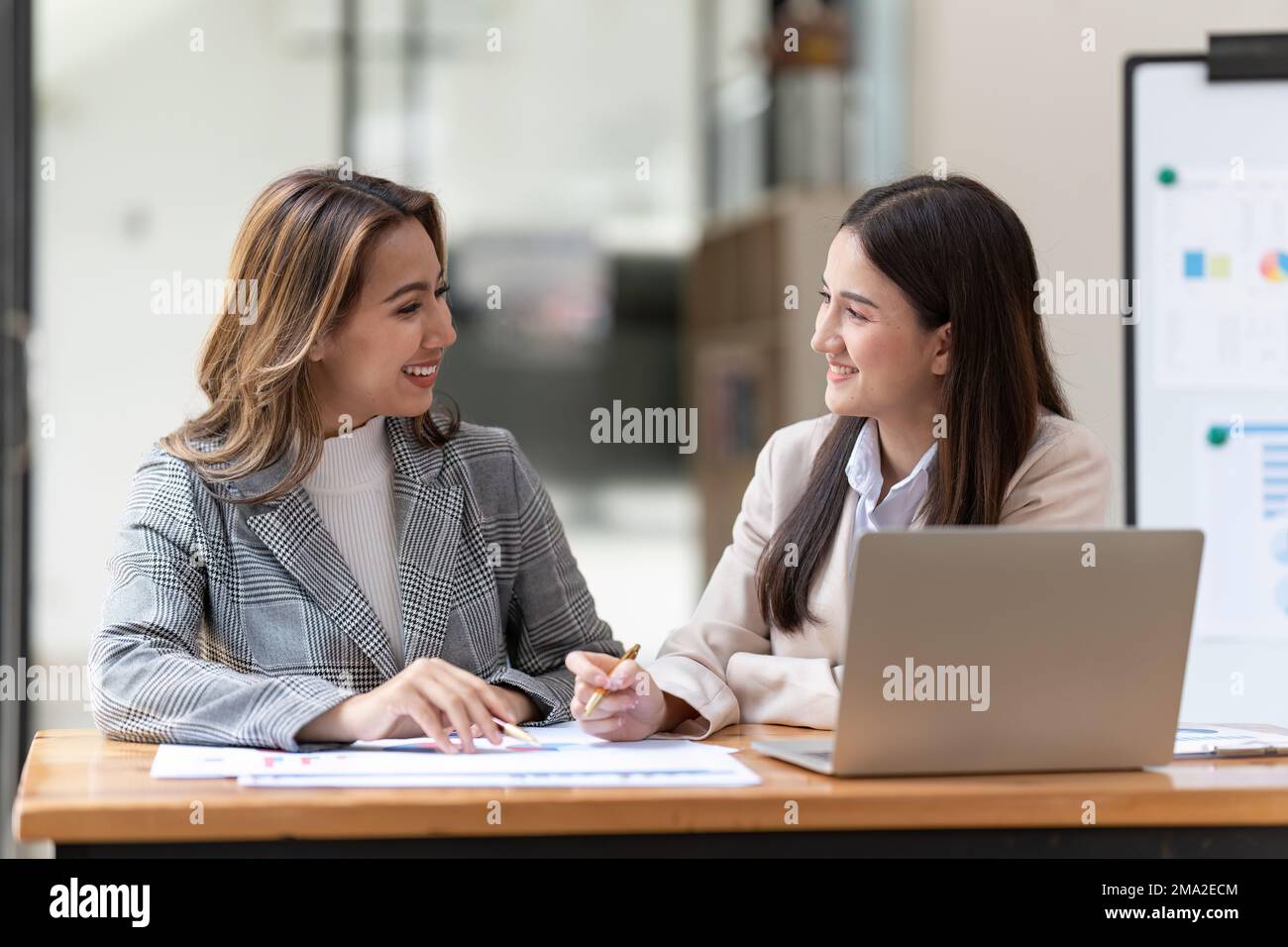 Working together on project. Two young asian business colleagues working on laptop computer. Stock Photo