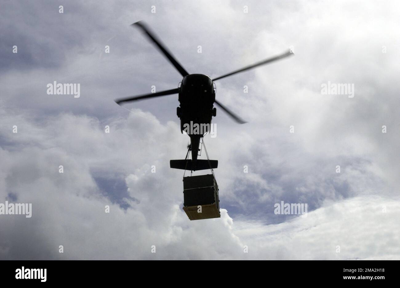 040726-F-0571C-055. [Complete] Scene Caption: A Colorado Army National Guard (COARNG) 2nd Battalion (BN), 135th Aviation Regiment (2/135th) UH-60 Blackhawk (Black Hawk) utility helicopter flies overhead carrying a sling loaded Container Express (CONEX) pallet of medical supplies to be transported to New Amsterdam, Berbice District, Guyana (GUY), from Camp Stephenson, Timehri, East Bank Demerara (EBD) District, GUY, as part of a Operation NEW HORIZONS 2004. This operation is a four-month joint service training exercise being held in Guyana by elements of the US Southern Command (USSOUTHCOM) and Stock Photo