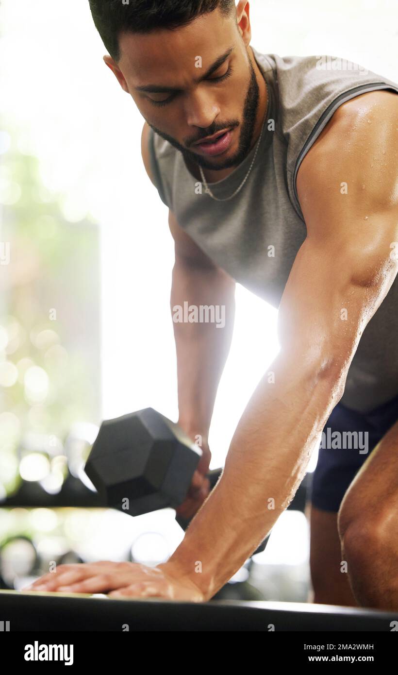 Nothing motivates you more than seeing results. a young man working out with dumbbells in a gym. Stock Photo