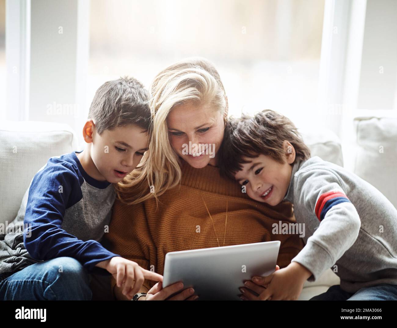 Love, tablet and mother with children on sofa bonding, quality time and relax on weekend together. Happy, family home and mom and kids with digital Stock Photo