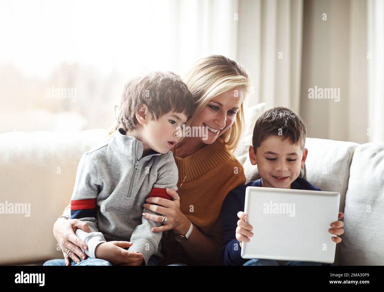Relax, tablet and mother with children on sofa bonding, quality time and content on weekend. Love, family home and mom and kids with digital tech for Stock Photo