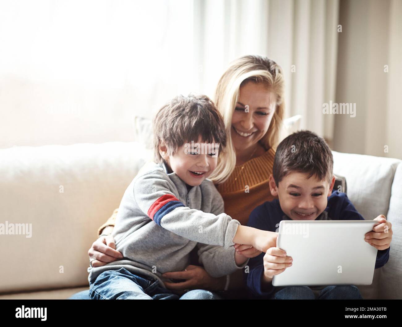 Family, tablet and mother with children on sofa bonding, quality time and relax on weekend together. Love, family home and mom and kids with digital Stock Photo