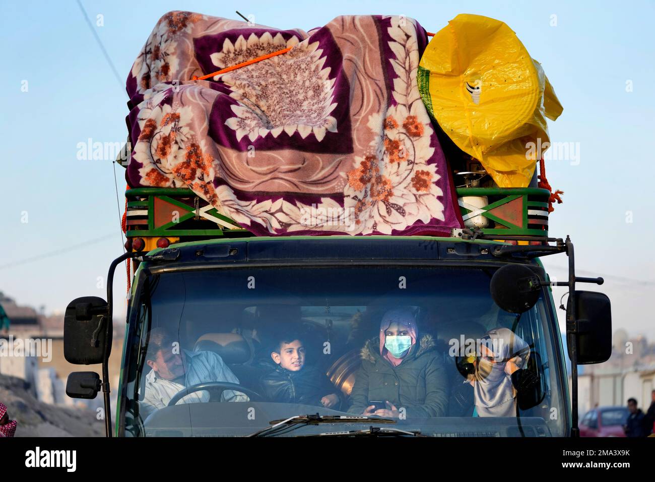 a-syrian-refugee-family-sits-inside-a-truck-with-their-belongings-as