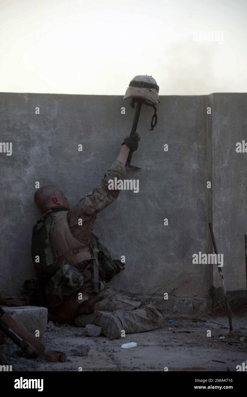 A US Marine Corps (USMC) troop with 1ST Battalion, 8th Marines, tries to lure insurgents to show their position by firing on a helmet extended out over a wall and into the open, during Operation Al Fajr, which is in support of Operation IRAQI FREEDOM. Subject Operation/Series: IRAQI FREEDOM Base: Fallujah State: Al Anbar Country: Iraq (IRQ) Stock Photo