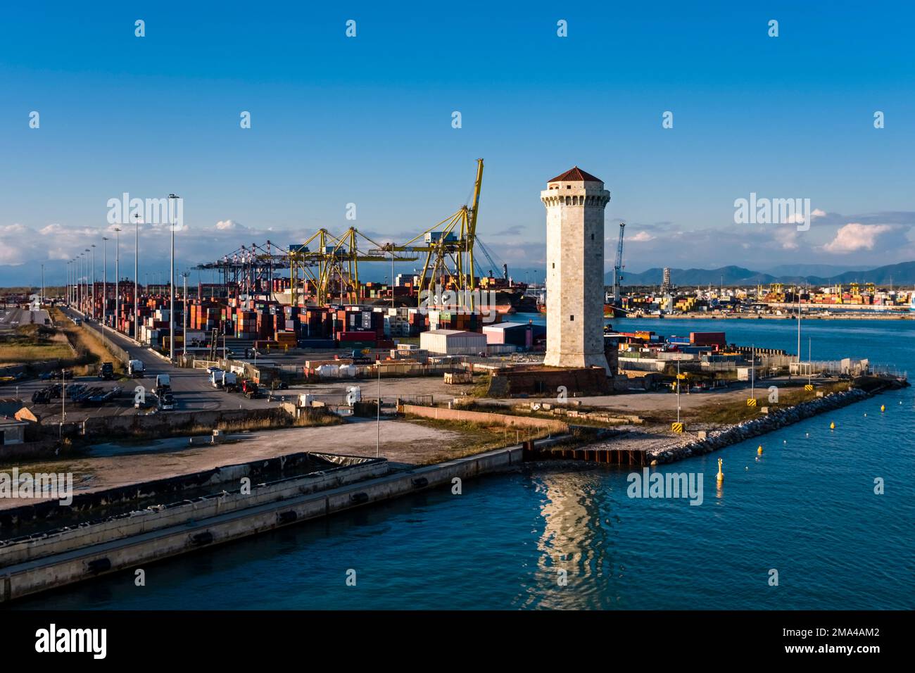Lighthouse, cranes unloading container ships at the container Port of ...