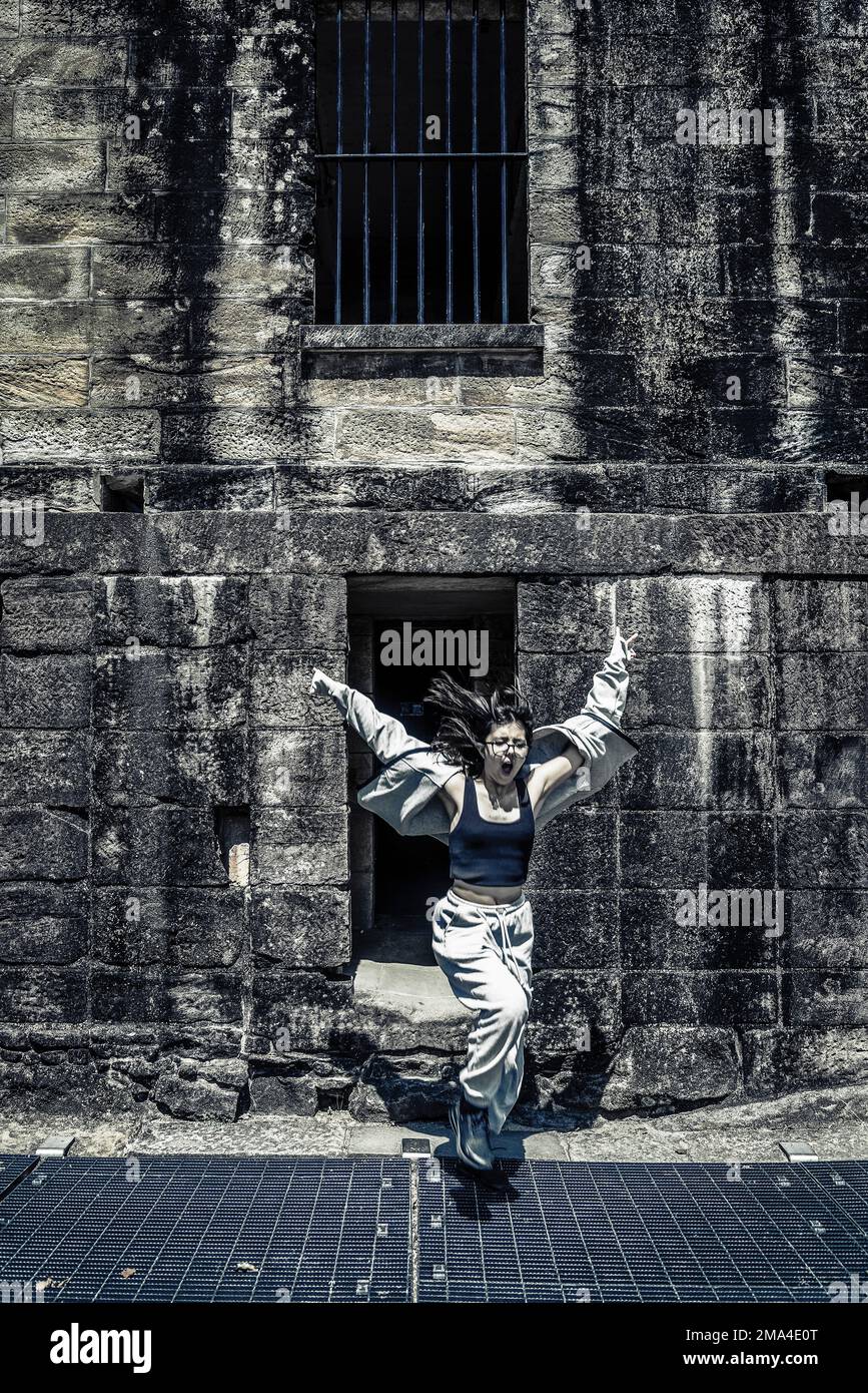 Girl jumping out in front of an old jail house Stock Photo