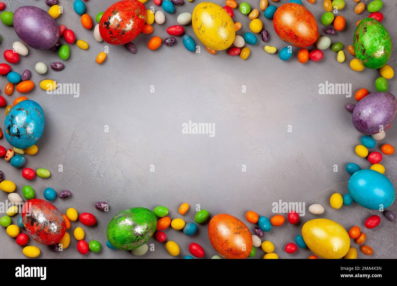 Colorful Easter eggs and chocolate Easter sweets  on grey background. Top view with copy space. Festive Easter concept. Stock Photo