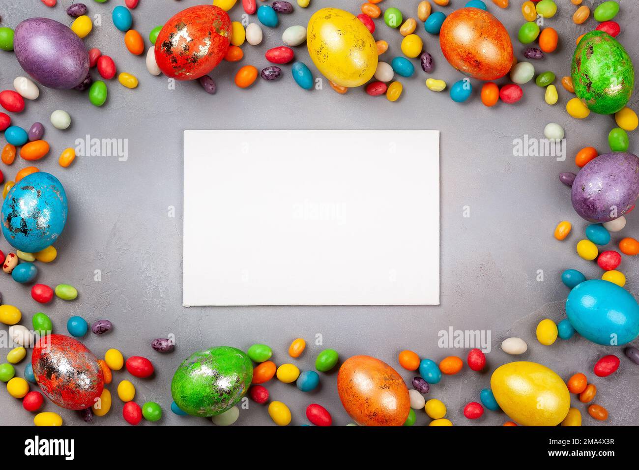 Colorful Easter eggs and chocolate Easter sweets on grey background. Top view with copy space. Festive Easter concept. Stock Photo