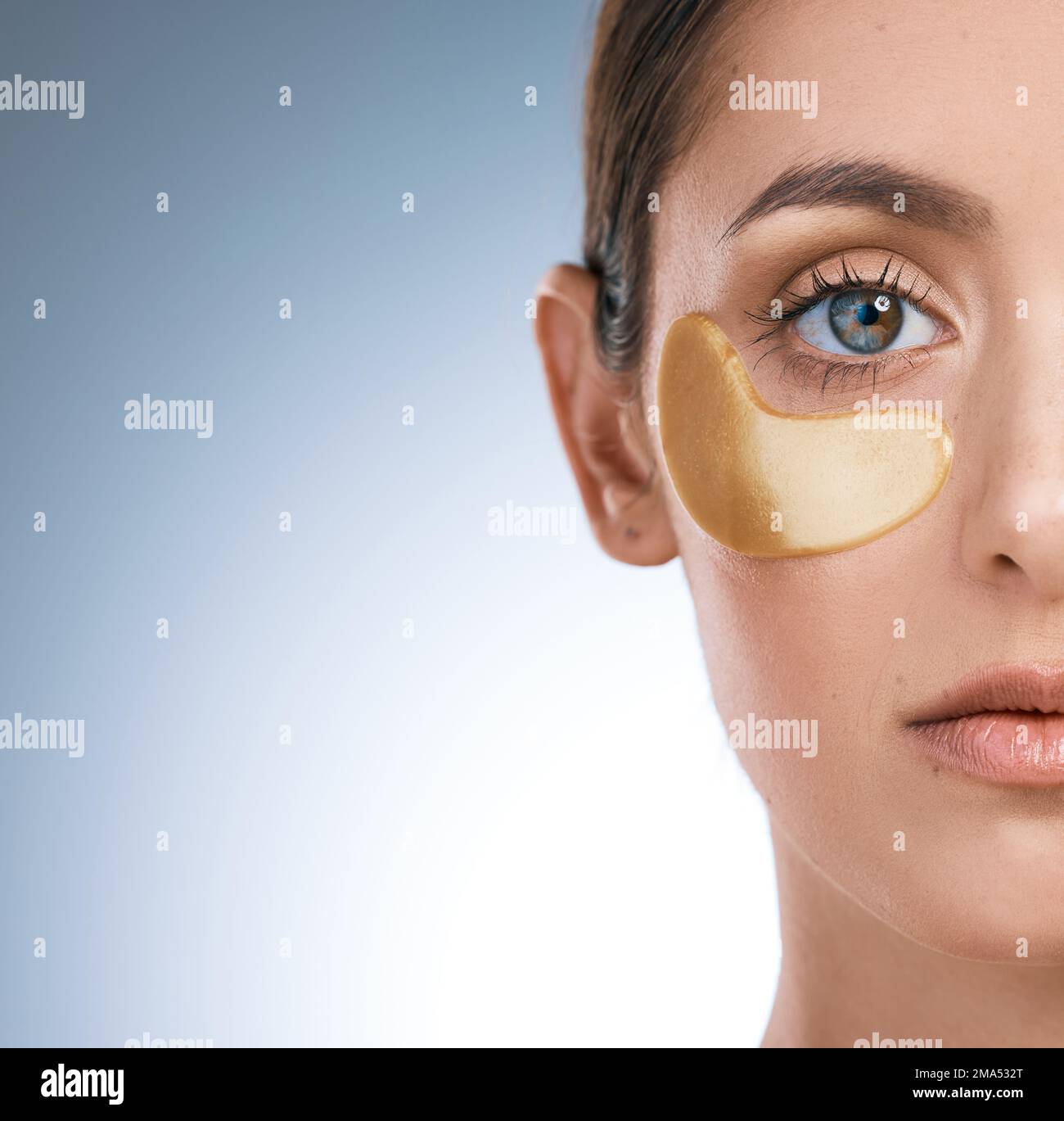 Dont let them hurt you ever. a young attractive woman wearing an under eye patch against a blue background. Stock Photo