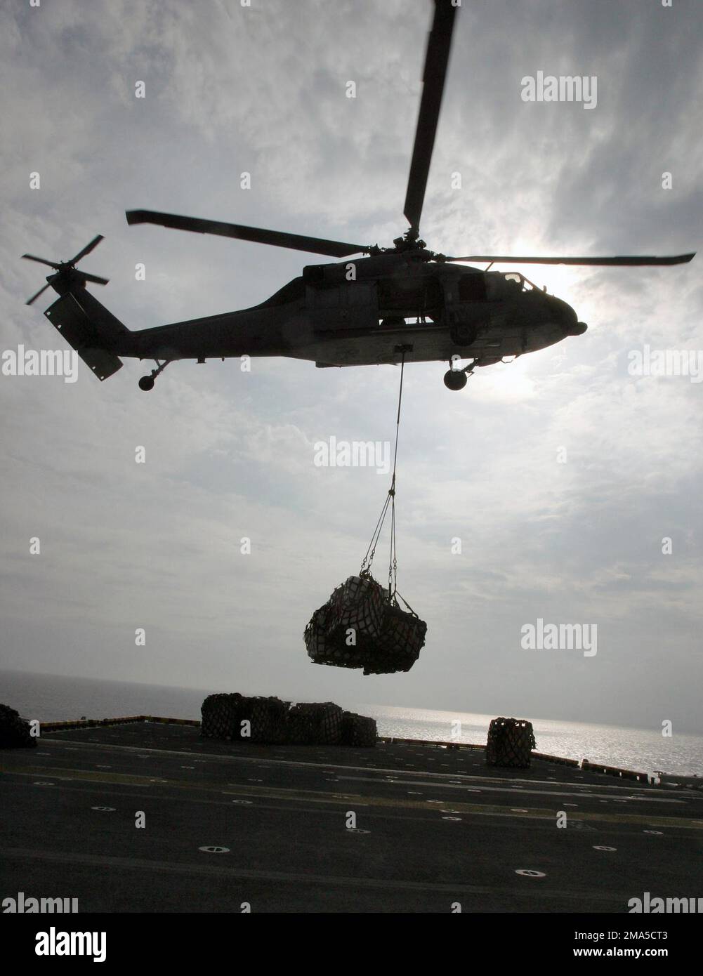 A US Marine Corps (USMC) MH-60S with the 15th Marine Expeditionary Unit (MEU) Special Operations Capable (SOC), delivers a cargo net full of humanitarian aid supplies onto the flight deck of the Amphibious Assault Ship USS BONHOMME RICHARD (LHD 6). The aid is being distributed to victims of the tsunami on the western side of Sumatra. Base: USS Bonhomme Richard (LHD 6) Stock Photo