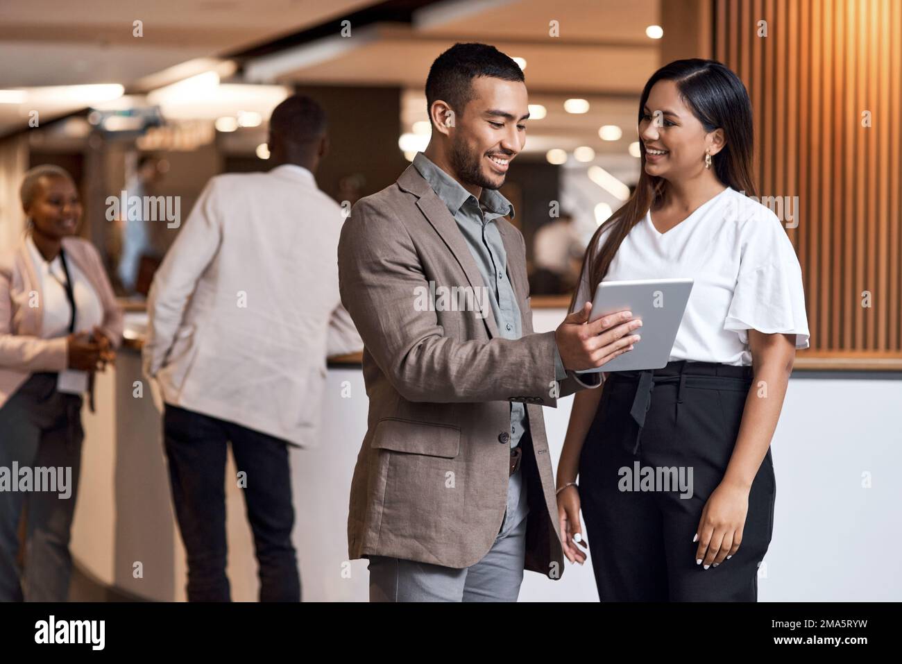 Meet with influential people and make your presence known. a young businessman and businesswoman using a digital tablet at a conference. Stock Photo