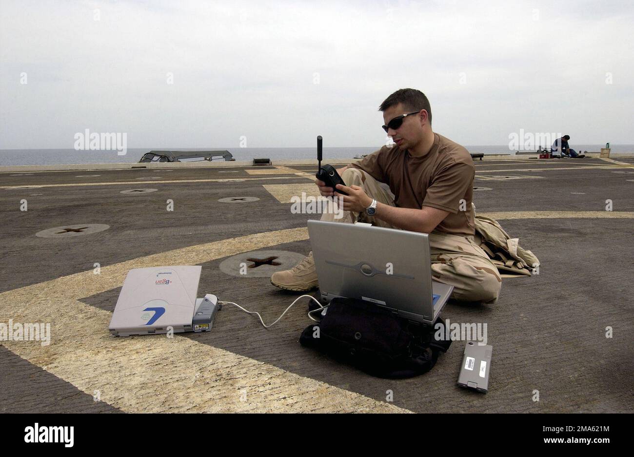 050419-N-7631T-002. [Complete] Scene Caption: US Navy (USN) Photographer's Mate First Class (PH1) Aaron Ansarov, attached to Fleet Combat Camera, Atlantic, calls his chief using an Iridium Satellite phone informing him of imagery being transmitted via Regional Broadband Global Area Network (RBGAN) satellite transmitter while onboard the Austin Class Amphibious Transport Dock ship USS DULUTH (LPD 6). Both Iridium and RBGAN allow deployed combat camera teams the ability to move imagery any time, anywhere with access to the Internet and phone lines in some of the most remote areas through out the Stock Photo