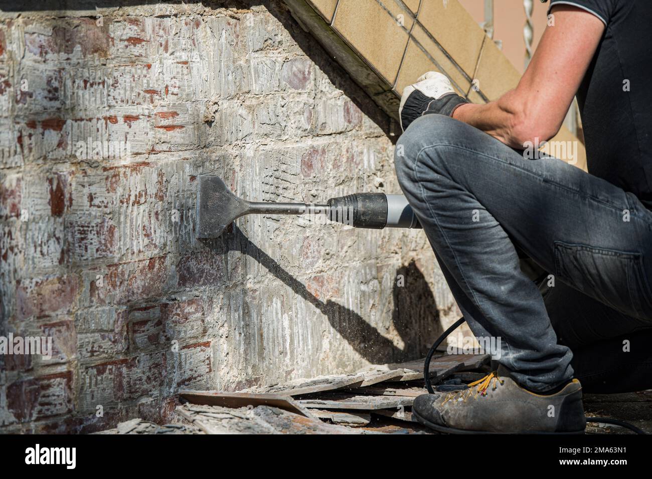 Man removes tiles from a wall with a hammer drill Stock Photo Alamy