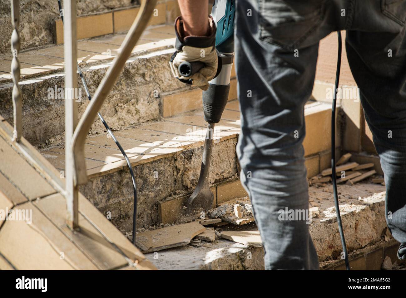 Man removes tiles from a stair using a hammer drill Stock Photo Alamy