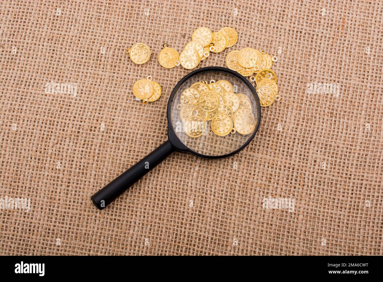 Plenty of fake gold coins behind magnifying glass Stock Photo Alamy