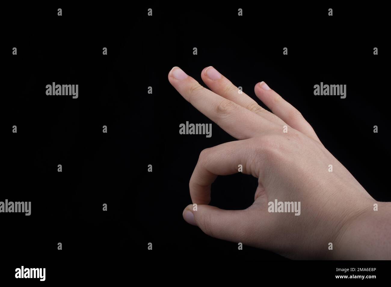 Hand gesturing sign ok okay agree on black background Stock Photo