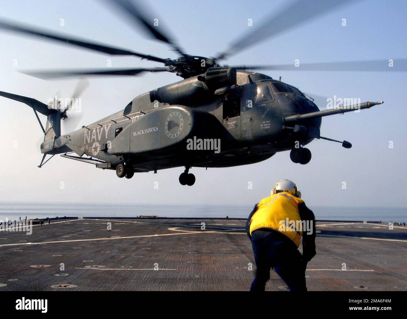 US Navy (USN) SEAMAN (SN) Devon Jamison waits in the foreground, as a ...