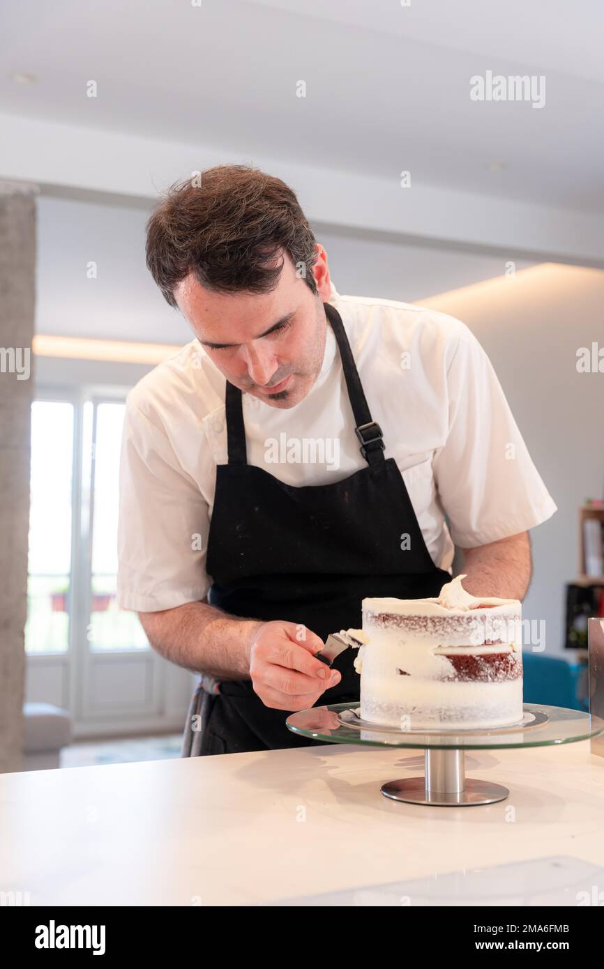 A challenger man bakes a red velvet cake at home, with the smoothing spatula leaving the perfect circle Stock Photo