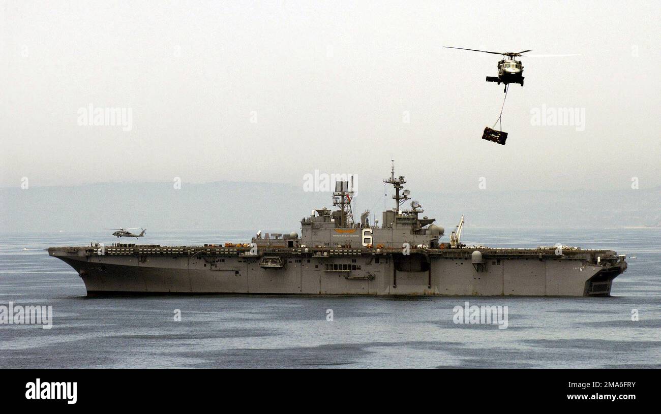 A port side view of the US Navy (USN) Wasp Class: Amphibious Assault Ship, USS BONHOMME RICHARD (LHD-6), showing USN MH-60S KnightHawk helicopters assigned to the 'Blackjacks' of Helicopter Sea Combat Squadron Two One (HSC-21), conducting Vertical Replenishment (VERTREP), in preparation for an upcoming Western Pacific deployment. Country: Pacific Ocean (POC) Stock Photo