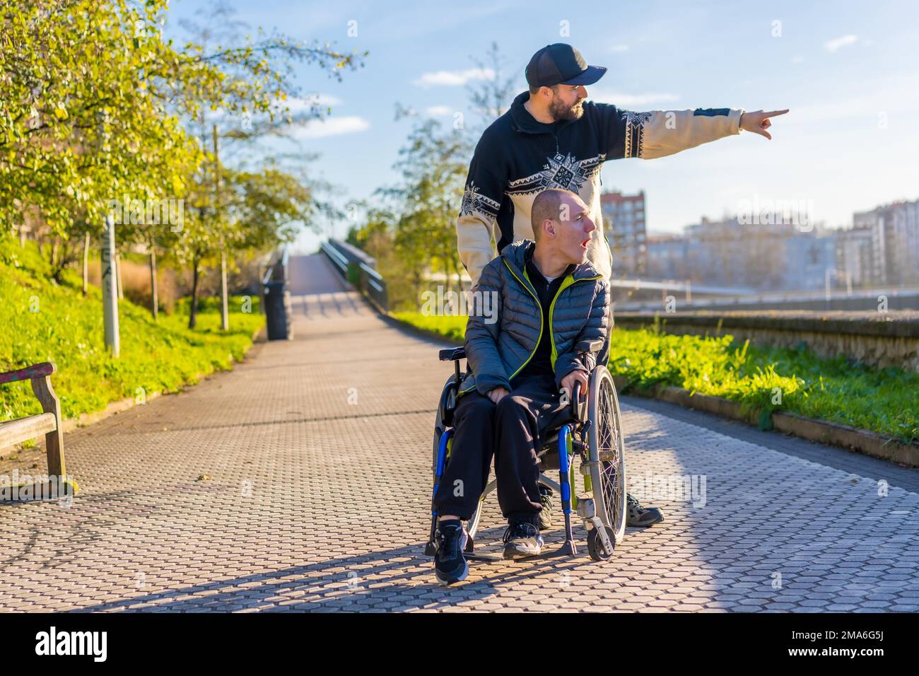 A disabled person in a wheelchair with an assistant enjoying a walk in