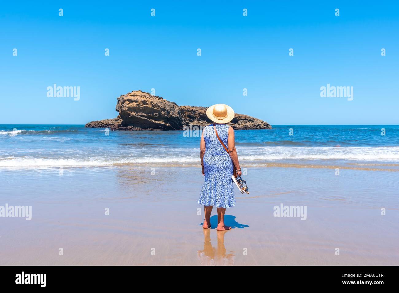 An elderly woman on vacation looking at the sea on the beach in Biarritz, Lapurdi. France, South West resort town Stock Photo