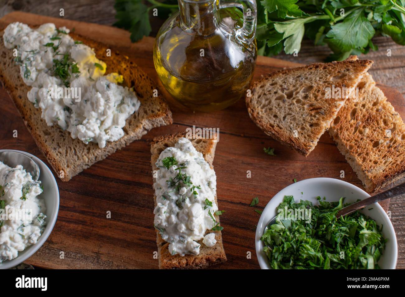Roasted or toasted Rye Bread with cottage cheese and herbs on wooden table. Stock Photo