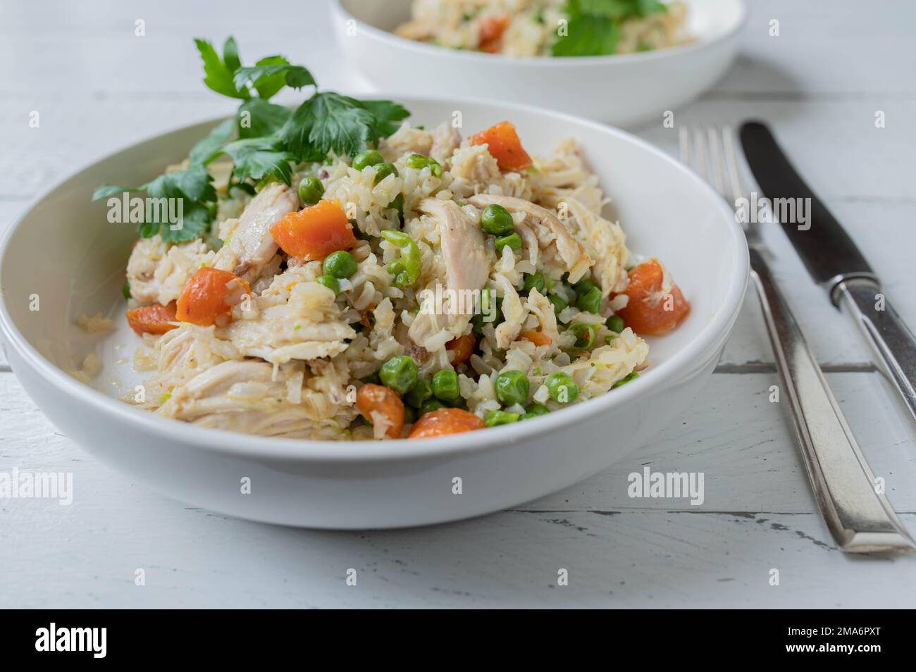 Brown rice with chicken and vegetables. on a plate with knife and fork on white background. healthy meal for fitness, diet or healthy eating Stock Photo