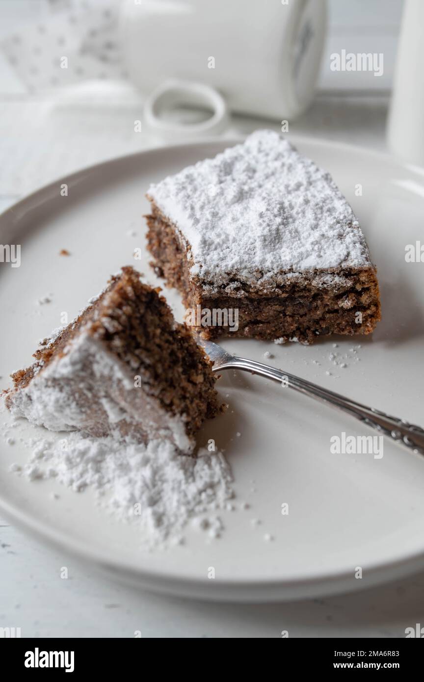 Flat chocolate cake with almonds, traditional italian torta caprese on a white plate Stock Photo