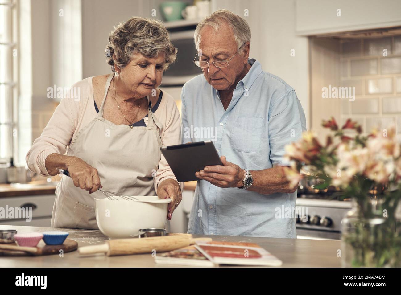 What ingredients do we need. a senior couple using a digital tablet while baking at home. Stock Photo