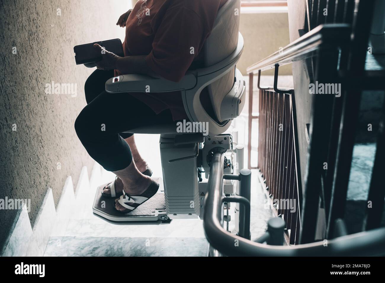 Aged woman needs modern assistance to go upstairs at home. Age problems concept. An electric