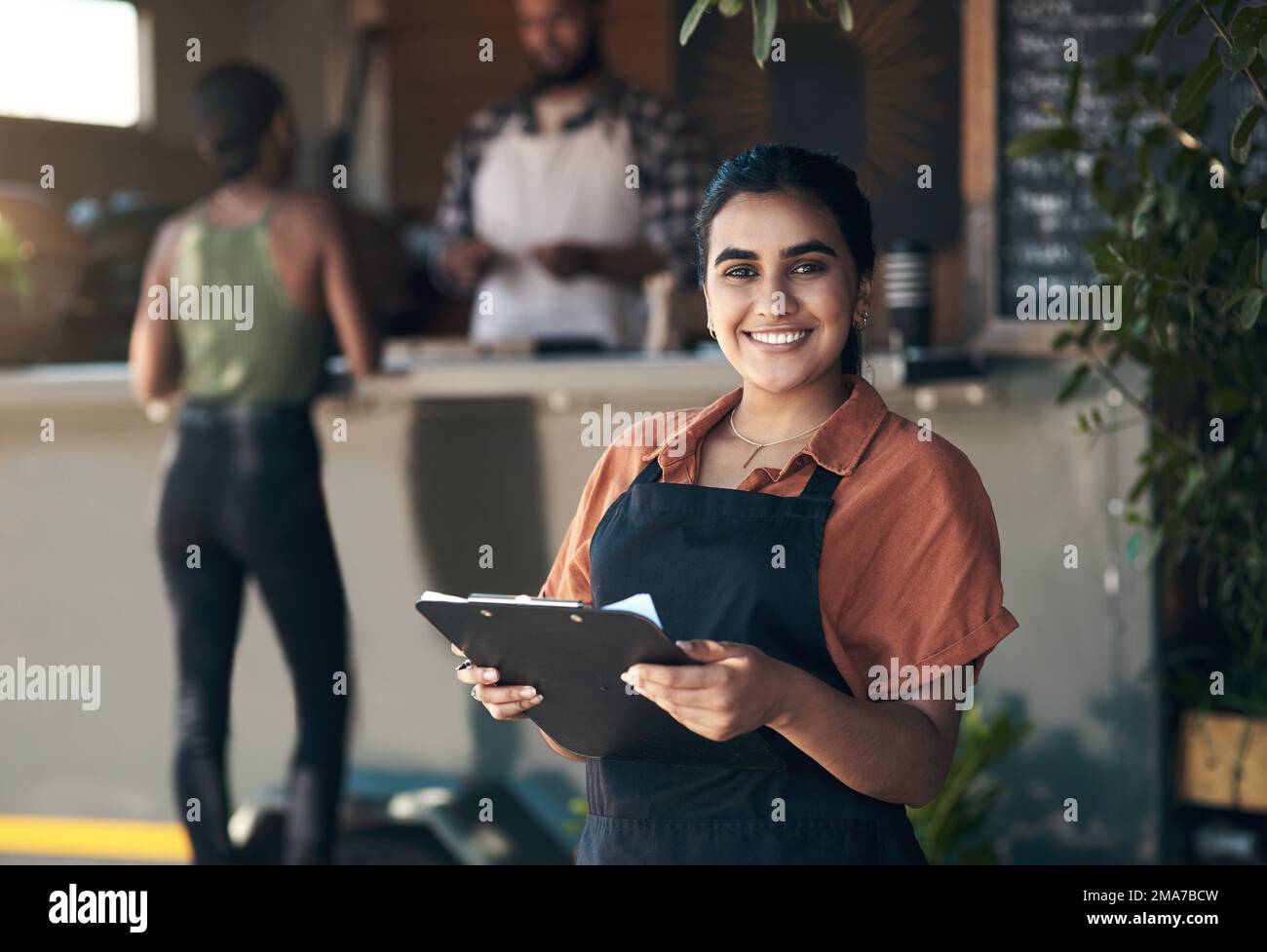 Table for. an attractive young woman standing outside her restaurant and holding a clipboard. Stock Photo