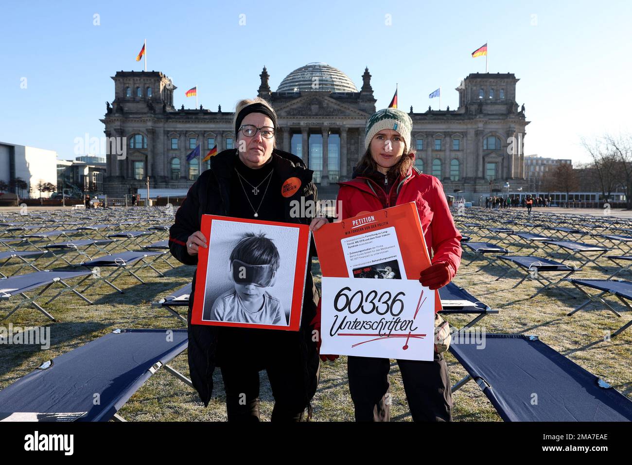 19 January 2023, Berlin: Ricarda Piepenhagen (l) and Elena Lierck demonstrate on behalf of LongCovid and ME/CFS sufferers in front of the Reichstag building. 400 cots with portraits of people affected from all over Germany have been set up on the lawn in front of the Reichstag building. A petition with over 60,000 signatures addressed to the German government will also be presented. The signatories are calling for the expansion of research and care structures. Therapy and medicine studies are needed, said initiator and applicant Piepenhagen. Photo: Joerg Carstensen/dpa Stock Photo