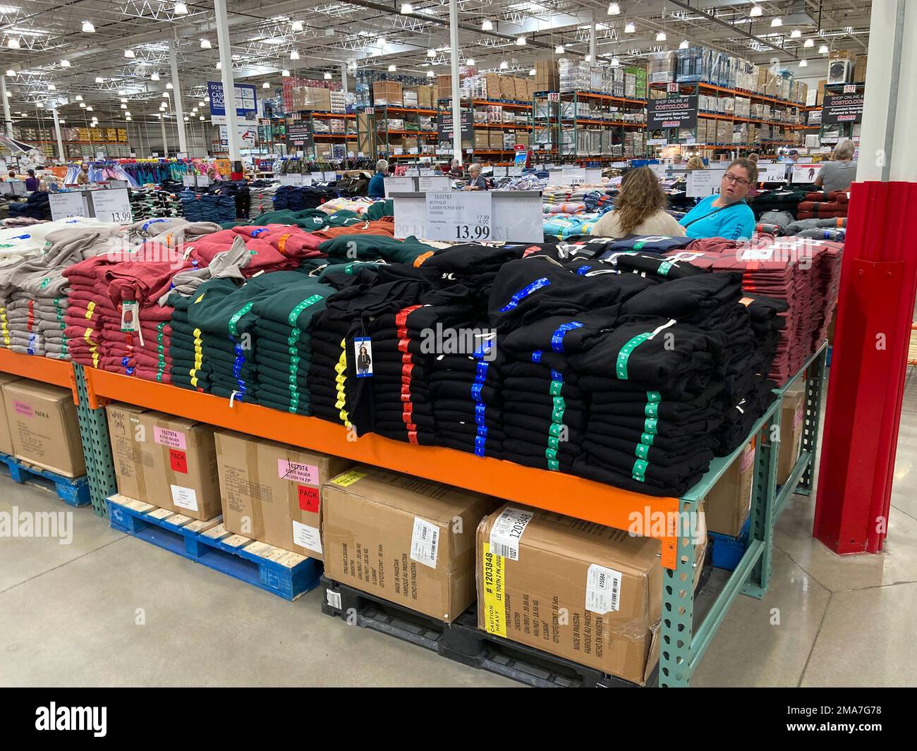 Shoppers Peruse Stacks Of Clothing On Display In A Costco Warehouse shoppers-peruse-stacks-of-clothing-on-display-in-a-costco-warehouse