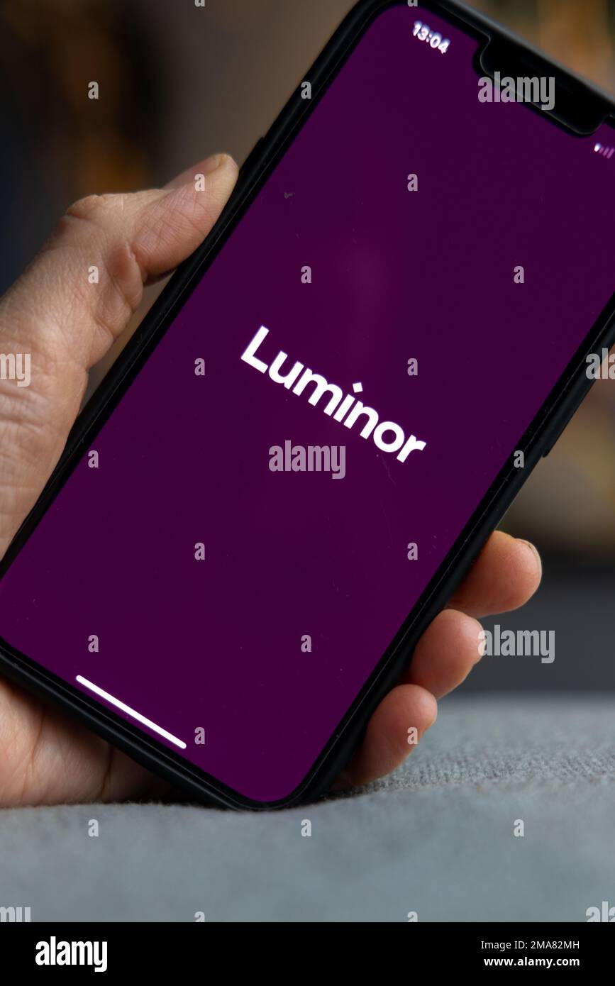 Hand holding a smartphone with Luminor bank icon on screen. White ...
