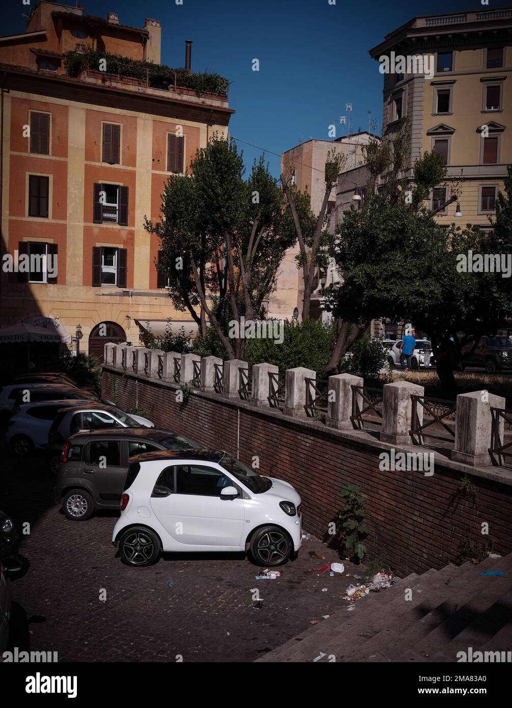 A white Smart car parked in Rome Italy at the end of a row of cars in a tight spot. Stock Photo
