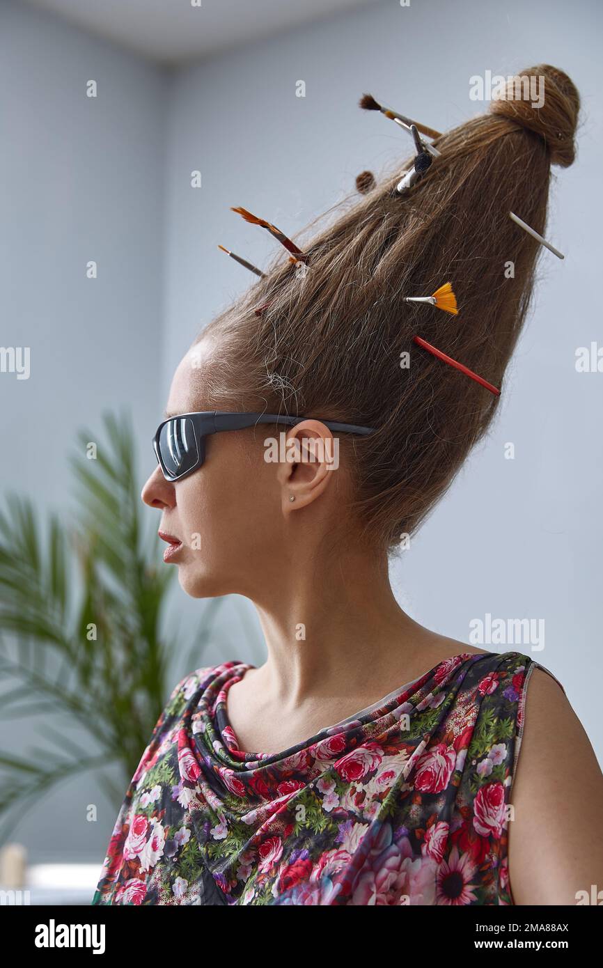 An extravagant woman in sunglasses with a strange hairstyle of long hair on her head. Stock Photo