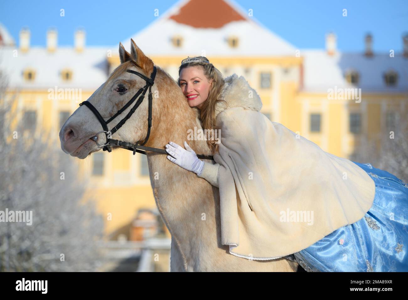 19 January 2023, Saxony, Moritzburg: Sandra Maria Huimann, actress of the  Landesbühnen Sachsen, sits in the role of Cinderella on the white horse  Jackson during a photo session in front of Moritzburg