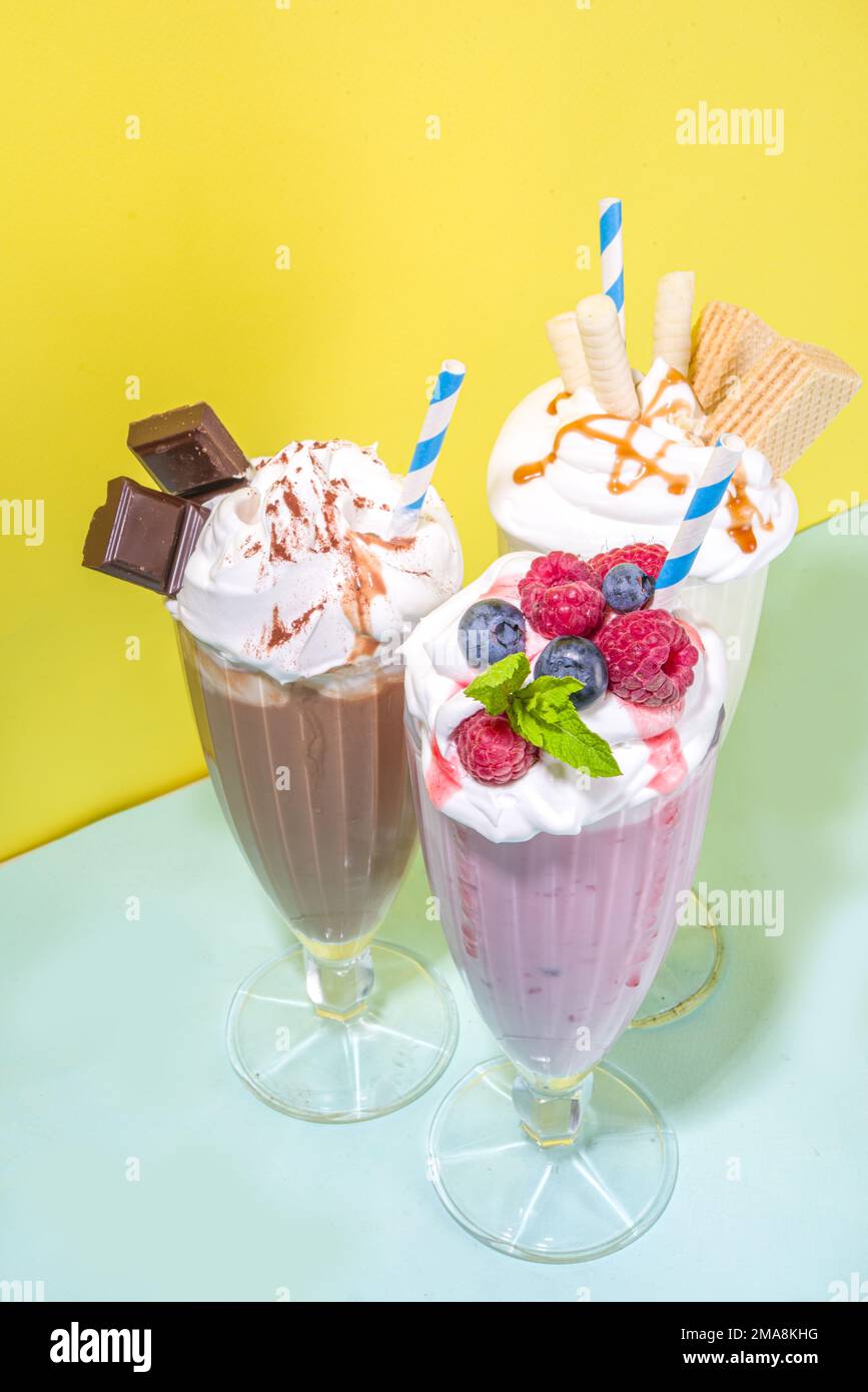 Summer refreshing drinks, milkshakes, crazy shakes with ice cream, berries, vanilla, chocolate. On a bright blue yellow background Stock Photo