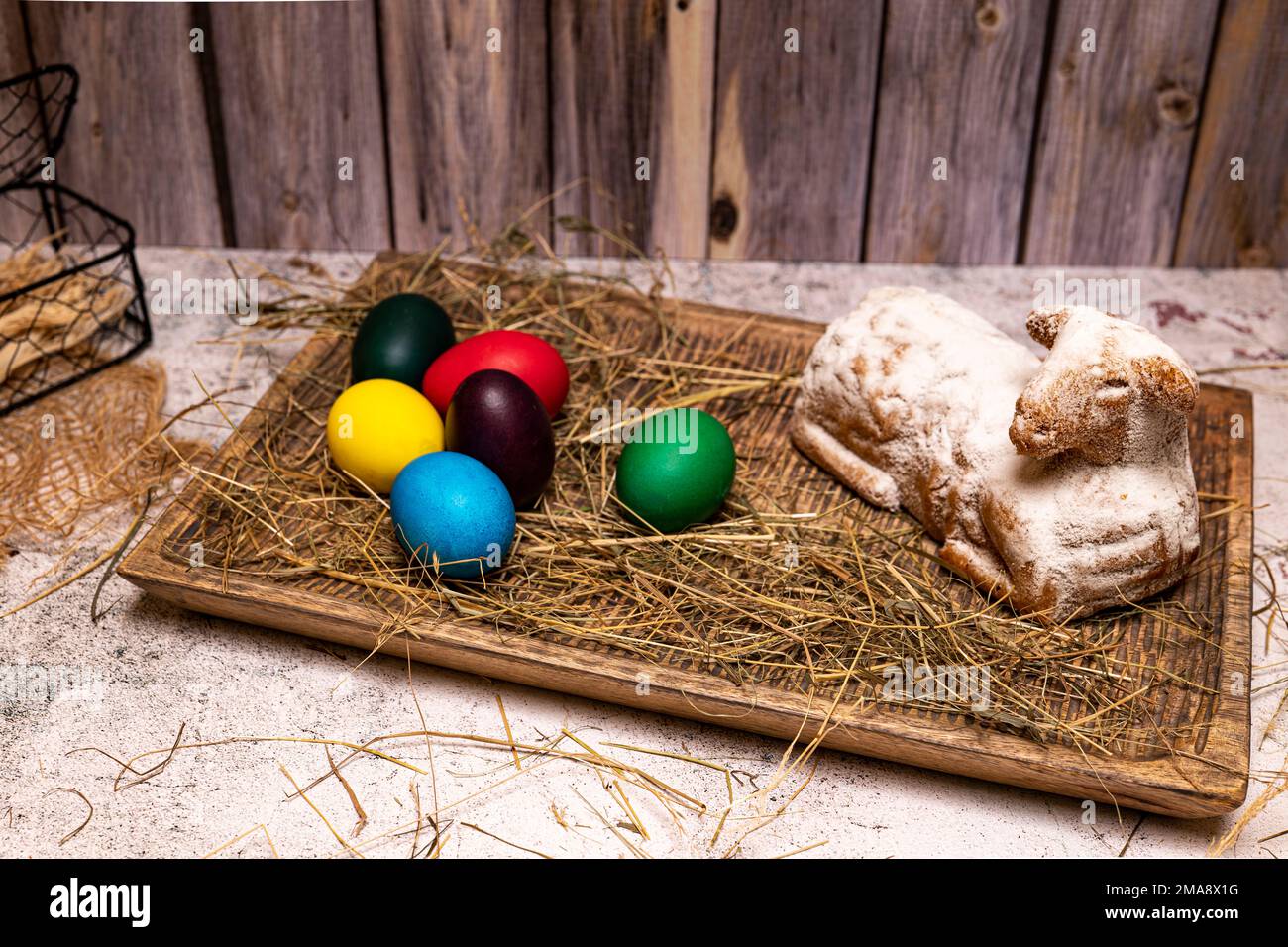 Easter lamb made of cake with colorful Easter eggs on straw, still life Stock Photo
