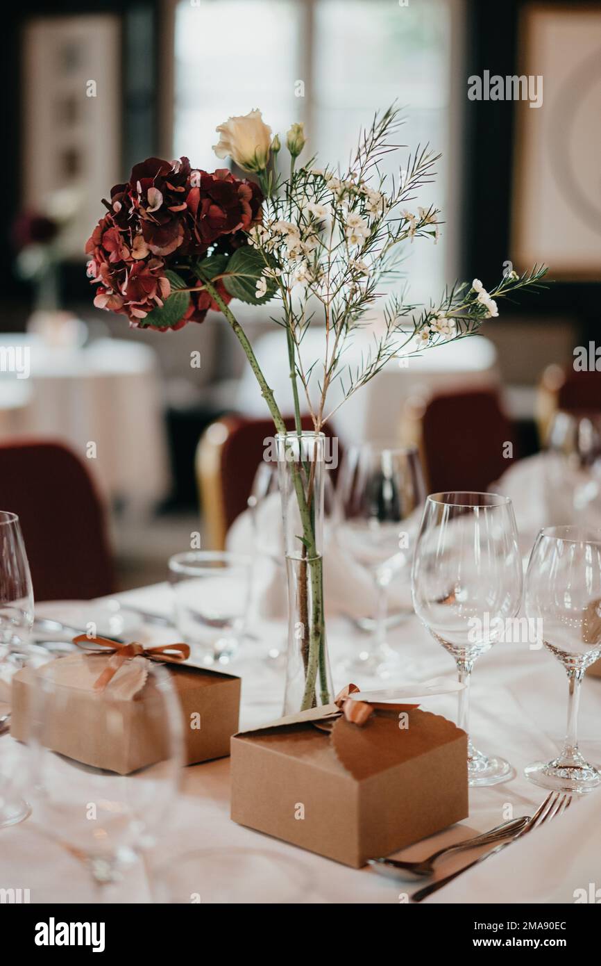 Bunte Blumen und Gastgeschenke auf gedecktem Hochzeitstisch Stock Photo
