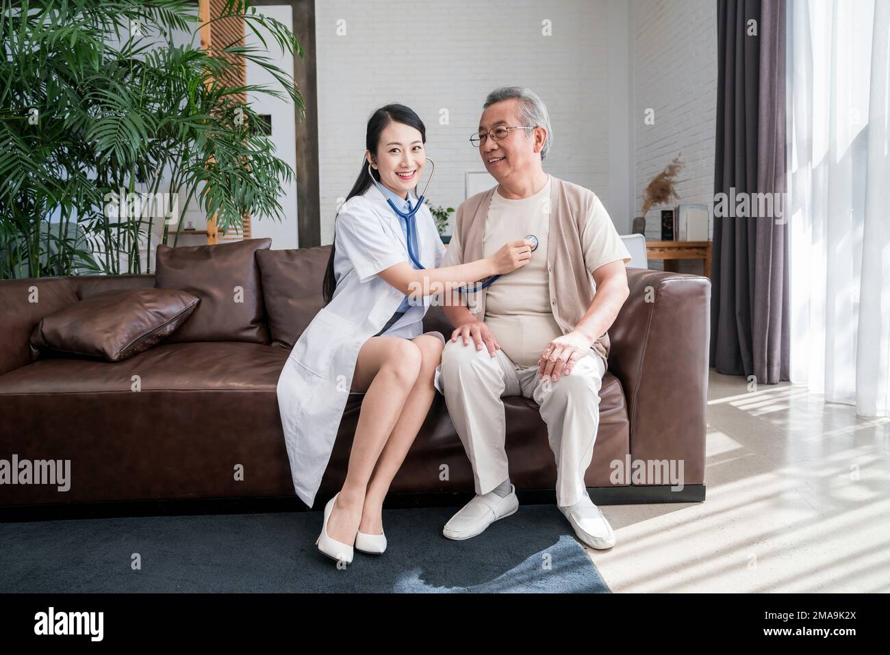 Young woman doctor to examine a older men Stock Photo