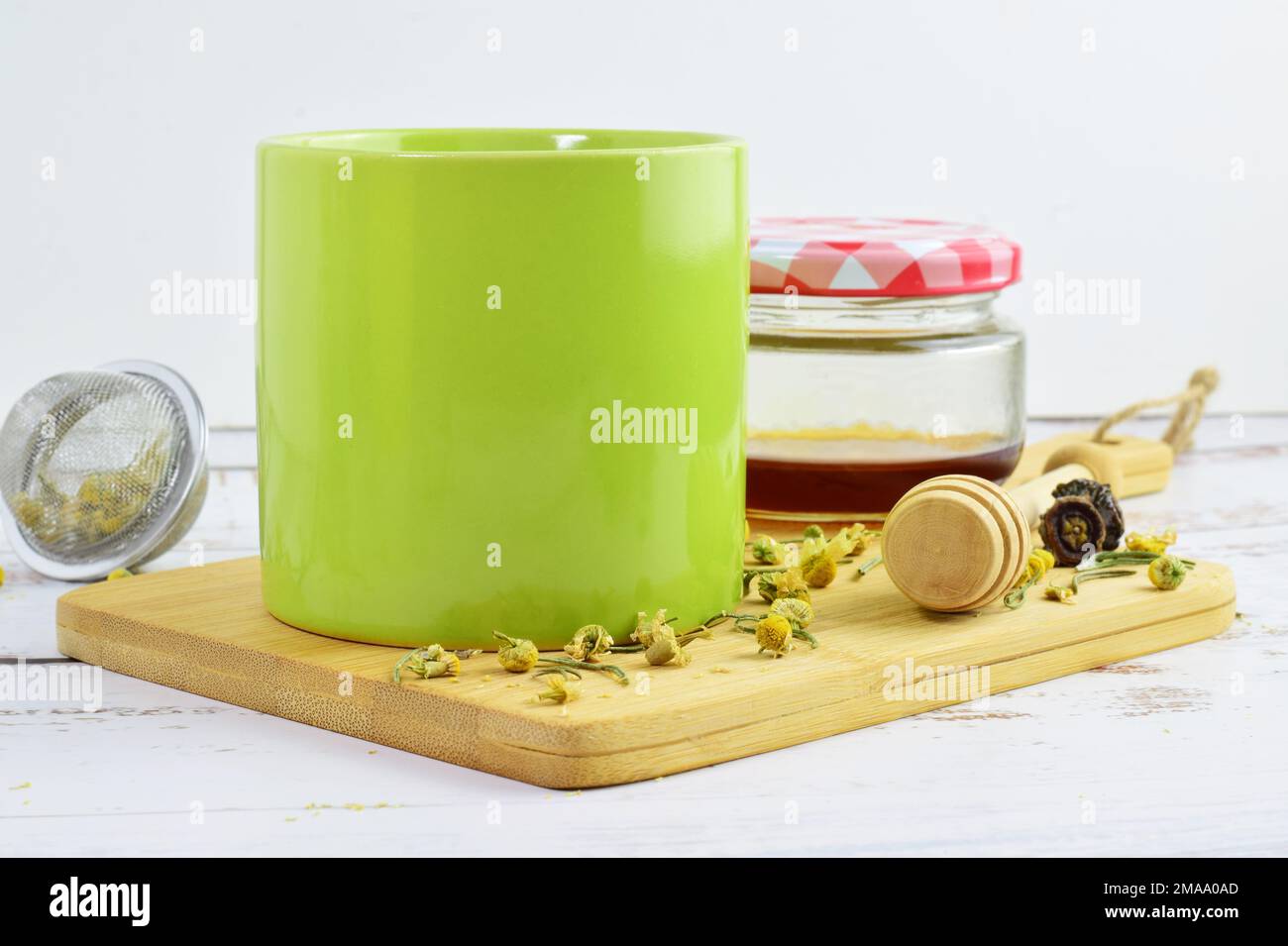 A beautiful view of a natural infusion of chamomile, rosemary, and honey, together with a green mug Stock Photo